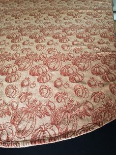 an orange and white table cloth with red designs on it, sitting on a black surface