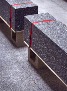 two concrete benches with red ribbon on them sitting in the middle of a floored area