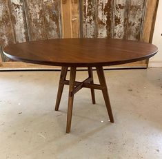 a round wooden table sitting in front of a wall with peeling paint on the walls