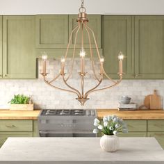 a kitchen with green cabinets and a chandelier hanging from the ceiling above it