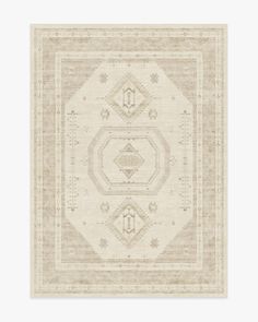 a beige and white rug with an intricate design on the middle, in front of a light gray background