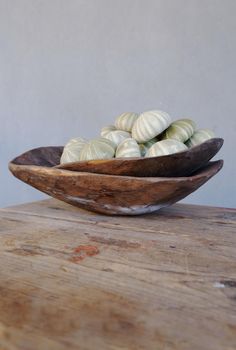 a wooden bowl filled with sea shells on top of a table