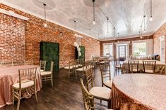 a banquet room with tables and chairs set up for a formal function in front of a brick wall