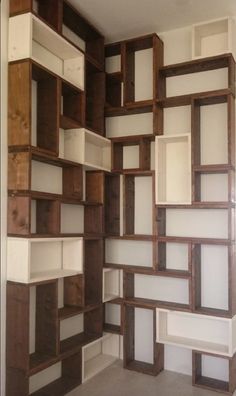 an empty room with shelves made out of wood and white paint on the walls,