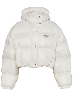 Re-Nylon detachable-sleeve padded jacket from PRADA featuring white, recycled nylon, down-feather filling, padded design, silver-tone hardware, detachable sleeves, enamel triangle logo, slouchy hood, high neck, front press-stud fastening, drop shoulder, long sleeves, elasticated cuffs and cropped. Conscious: This item is made from at least 50% recycled or upcycled materials. For recycled synthetic clothing products we highly recommend using a microfibre-catching washing bag to ensure that no mic White Puffer Jacket, White Puffer, Cropped Puffer Jacket, Triangle Logo, Outerwear Women