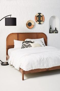 a bed with white sheets and pillows in a bedroom next to two wall hangings