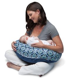 a woman sitting on the floor holding a baby in a blue and white patterned sling