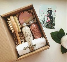 an open box with various items in it on a table next to flowers and candles