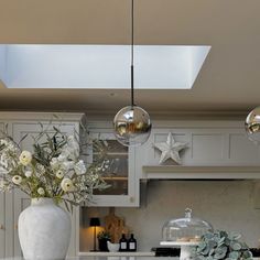 a white vase filled with flowers sitting on top of a kitchen counter under a skylight