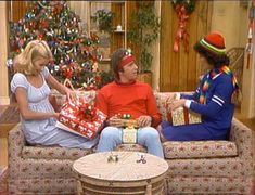 three people sitting on a couch with presents