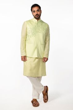 Mint green bam silk kurta with mirror embroidery. Comes with ivory cotton silk pyjama pant and a bundi with welt pockets.
Components: 3
Pattern: Hand embroidered
Type Of Work: Mirror
Neckline: Mandarin collar
Sleeve Type: Bundi : Sleeveless, Kurta : Full
Fabric: Kurta and Bundi : Bam silk, Pant : Cotton silk
Color: Green
Other Details: 
Side slits on kurta
Closure : Front buttons
Occasion: Mehendi and Haldi, Sangeet - Aza Fashions Spring Sherwani With Gota Work, Spring Wedding Sherwani With Gota Work, Green Chanderi Sherwani With Cutdana Details, Green Chanderi Sherwani With Cutdana, Festive Green Chanderi Bandhgala, Silk Nehru Jacket For Eid Reception, Silk Nehru Jacket For Reception During Eid, Green Bollywood Sherwani In Chanderi Fabric, Bollywood Style Green Chanderi Sherwani