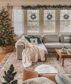 a living room filled with furniture and a christmas tree in front of a window on top of a rug