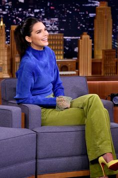 a woman sitting on top of a blue couch in front of a cityscape