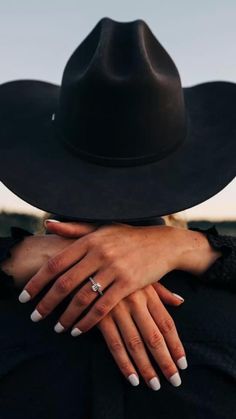 two hands holding each other while wearing a black hat