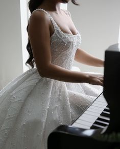 a woman in a white dress is playing the piano