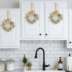 christmas wreaths are hung on the kitchen cabinets