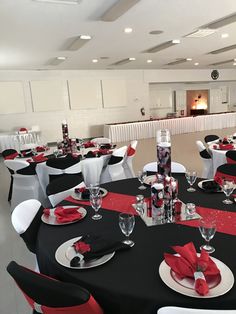 a banquet room set up with black and white tables, red napkins and silverware