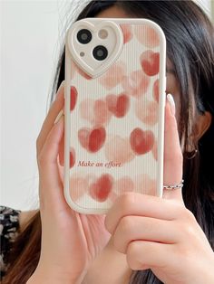 a woman holding up a cell phone case with red hearts on the front and bottom