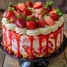 a cake covered in strawberries and cream on top of a black plate with wooden table