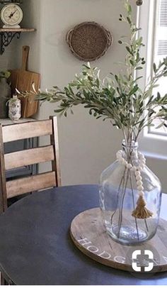 there is a vase with some flowers in it sitting on the table next to a clock