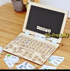 an open laptop computer sitting on top of a wooden table covered in cut out letters