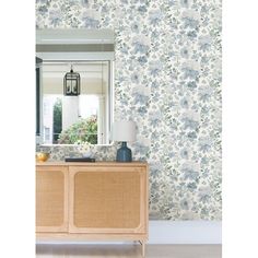 a room with floral wallpaper and a dresser in the foreground, mirror above it