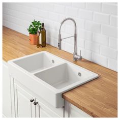 a white kitchen sink sitting on top of a wooden counter