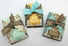 three wrapped gift boxes with brown and blue ribbon tied around the top one has a bow on it