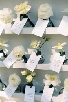 white flowers in vases with cards attached to them