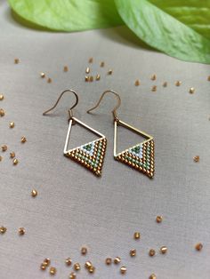 Step into the timeless charm of our 'Grecian Olive Grove Earrings.' Handcrafted with love and precision, each earring showcases a Stainless Steel Gold link anchoring a harmonious blend of olive green hues, luxurious gold, and a touch of pristine white Miyuki beads. Utilizing the ancient technique of bead weaving, specifically brick stitch, this modern design captures the essence of an olive grove in the heart of Greece. The gracefully shaped triangles elevate your style, creating an accessory th Minimalist Earrings Gold, Olive Grove, Brick Stitch Earrings, Jewelry Minimalist, Earrings Beaded, Bead Work Jewelry, Miyuki Beads, Triangle Earrings, Brick Stitch