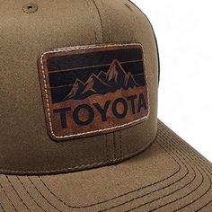 Get nostalgic with our Vintage Style Toyota Laser Engraved Leatherette Patch Trucker Hat featuring the Toyota Mountains logo! Classic design meets modern flair. Elevate your style with comfort. Embrace the road ahead in timeless fashion. Classic Brown Hat For Outdoor Activities, Classic Brown Baseball Cap For Outdoor, Vintage Brown Travel Hat, Brown Flat Bill Travel Hat, Brown Retro Hat For Outdoor, Brown Flat Bill Hat For Outdoor, Brown Trucker Hat With Logo Patch For Outdoor, Retro Leather Cap, Brown Trucker Hat For Outdoor Activities