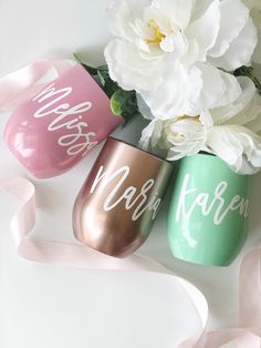 three painted wine glasses sitting next to each other on top of a table with flowers