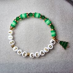 a green and white beaded bracelet with the word season written in gold on it