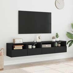 a living room with a large flat screen tv on the wall and plants in front of it