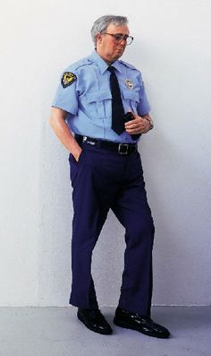 a man in a police uniform leaning against a wall with his hands on his hips