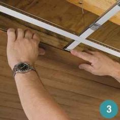 a man is working on the ceiling in his house with wood and metal trimmings