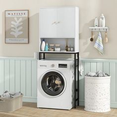 a washer sitting next to a dryer in a room with white walls and wood flooring