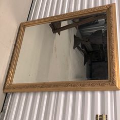 a gold framed mirror hanging on the side of a metal wall next to a door