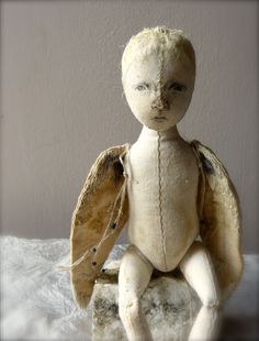 an old doll with wings sitting on a white surface