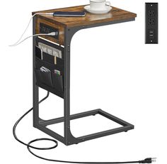 a computer desk with an electrical outlet plugged in to it and a cup on top