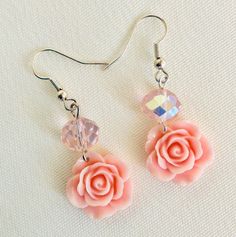 These adorable little dangle earrings feature a pale pink acrylic rose bead and a round faceted iridescent glass bead. They measure 1 and 3/4 inches in length from ear to end, and hang by silver hook. They are truly cute and simple, but fun. The perfect addition to any spring or summer outfit Earrings: 1.75 inches FREE FIRST CLASS SHIPPING ON ALL JEWELRY ORDERS! Pink Dangle Jewelry With Rose Design, Pink Rose Design Dangle Jewelry, Pink Flower Charm Dangle Jewelry, Pink Flower Crystal Earrings For Gift, Pink Rose Design Drop Earrings, Pink Dangle Flower Earrings For Mother's Day, Pink Drop Earrings For Spring, Pink Flower Jewelry With Rose Design, Feminine Pink Jewelry With Rose Design