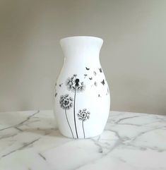 a white vase sitting on top of a marble table covered in black and white flowers