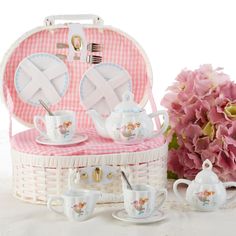 a tea set in a basket with pink flowers