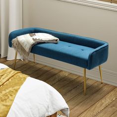 a blue bench sitting on top of a hard wood floor next to a white bed