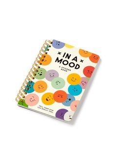 an in a mood notebook with smiley faces on the front and back cover, sitting on a white surface