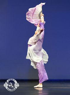 a woman is dancing with an umbrella in her hand and holding it up to the side