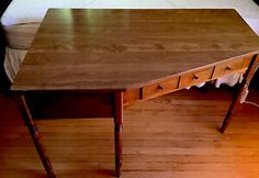 an old wooden desk with two drawers on it's sides, in front of a bed