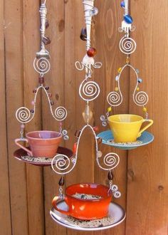 three tiered trays with cups and saucers hanging from the side on a wooden fence