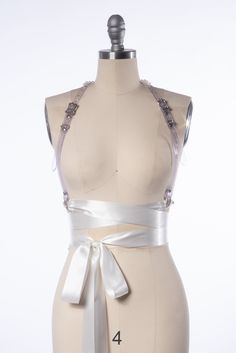 High quality, durable-yet-delicate bespoke harness made in clear or white PVC and embellished with spherical pearl rivets.Luxurious wide satin ribbons wrap around the waist and tie into a bow, and the ends are trimmed with tassels. Silver toned nickel plated steel hardware. Shown in Clear PVC and White PVC. Custom sizing available. All pieces are MADE TO ORDER, standard sizes XS-4XL. If your measurements fall outside these standards or you are unsure of what size to order, select "CUSTOM" and in Ribbon Harness, Dark Gothic Aesthetic, Body Harness Outfits, Harness Outfit, Pearl Ribbon, Tassel Belt, Satin Ribbons, Gothic Accessories, Ribbon Belt