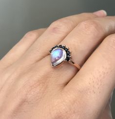 "A unique cabochon teardrop Genuine rainbow moonstone ring accented with a crown of 9 petite Genuine black diamond handcrafted in solid 18k Gold. Wrapped in a box ready for gift-giving. (R egt 98) Final Sale as it will be handcrafted just for you -----> Also if you prefer another gemstone just convo us with your request. Instagram Video --------------- https://www.instagram.com/p/ByYvrQ5BrwX/?igshid=710mit76srd5 Ring Info ----------------- 18k Rose Gold or White Gold or Yellow Gold Ring Shank Elegant Pear-shaped Moonstone Ring, Fine Jewelry Pear-shaped Moonstone Ring, Fine Jewelry Teardrop Moonstone Ring, Elegant Teardrop Moonstone Ring, Fine Jewelry Moonstone Teardrop Ring, Teardrop Moonstone Gemstone Ring, Teardrop Moonstone Jewelry With Rose Cut Diamonds, Teardrop Cabochon Jewelry For Wedding, Rainbow Moonstone Engagement Ring